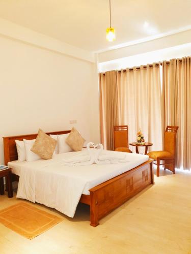 a bedroom with a large bed and two chairs at Hotel Helani Pvt Ltd in Midigama East