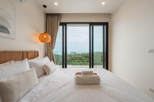 a bedroom with a white bed with a large window at Staylar Sunrise Villas - Chaweng Noi, Koh Samui in Amphoe Koh Samui
