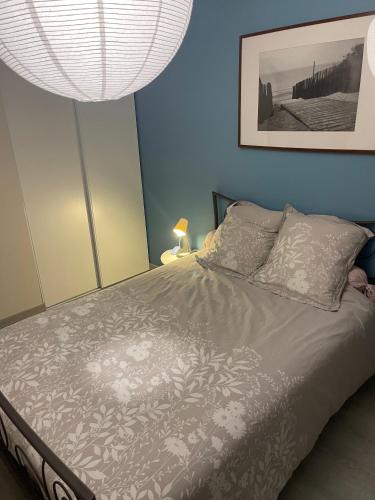 Una cama en un dormitorio con una pared azul. en Chambre cosy entre ville et campagne, en Lorette