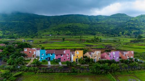 a small village in a field with mountains in the background at Touchwood Bliss Resort - Igatpuri in Nashik