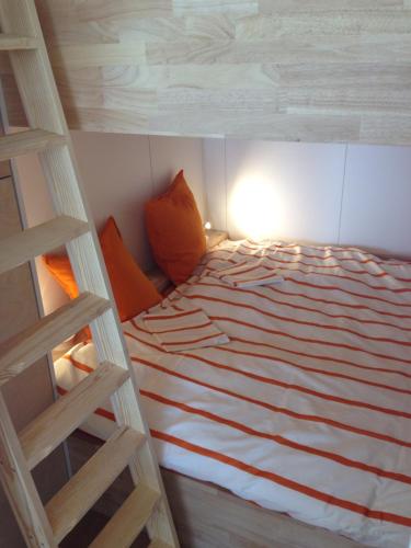 Una cama con almohadas naranjas y una escalera en una habitación en Studio Zeezicht, en Ostende
