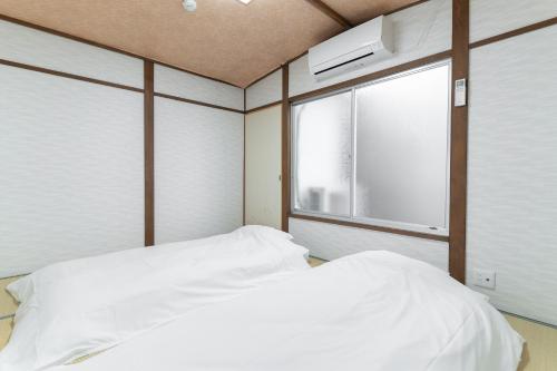 a bedroom with two beds and a window at 蛮子民宿 金閣寺 in Kyoto
