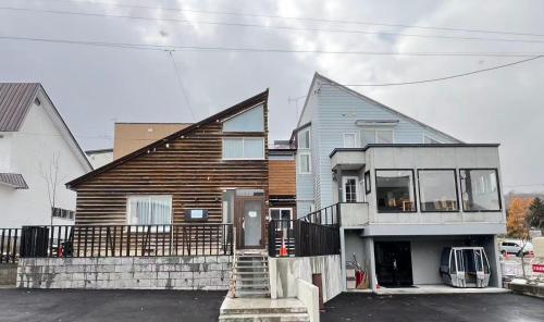 a large wooden house with a staircase in front of it at 雪玉Snowball Hostel in Furano