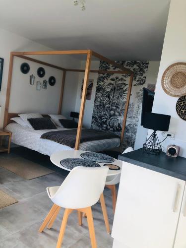 a bedroom with a bed and a table and chairs at Bel Air Studios-Terrasse couverte-Jardinet-Vue Pont de Normandie-Parking privé in Honfleur