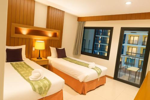 una camera d'albergo con due letti e una finestra di Prisha Inn a Patong Beach