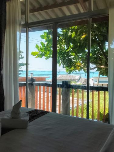 a bedroom with a view of the ocean through a window at The Sea @ Lanta Hotel in Ko Lanta