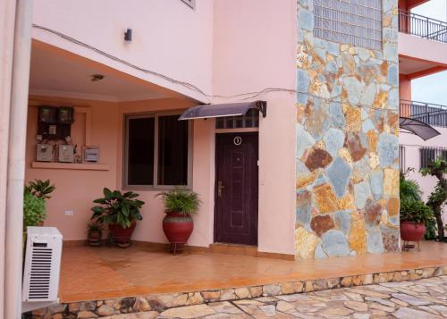 una casa con una puerta negra y una pared de piedra en VERA's TOWERS, en Accra