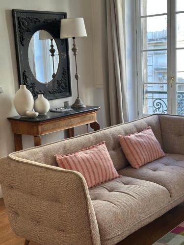 un soggiorno con un divano e uno specchio di Escale citadine au centre d'Avignon, climatisation, appartement de charme, spacieux et lumineux ad Avignone