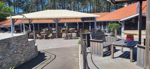 an outdoor patio with a bench and a restaurant at L'Escapade Seignossaise in Seignosse