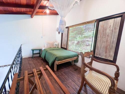 Rowinrich Cottages في إيلا: غرفة بها سرير وكرسي على أرضية خشبية