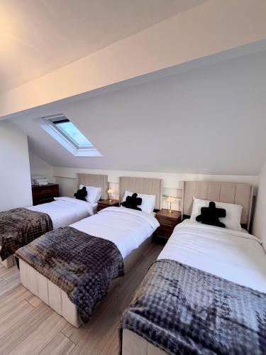 a bedroom with three beds with black pillows at Lux 4 Bedroom House - Jacuzzi Bath Sleeps 9 Free Parking Near Leeds Centre in Leeds