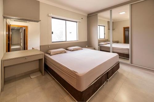 una camera da letto con un letto grande e uno specchio di Casa Munique Maringa a Maringá