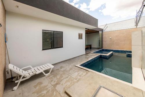 una piscina con una sedia accanto a un edificio di Casa Munique Maringa a Maringá