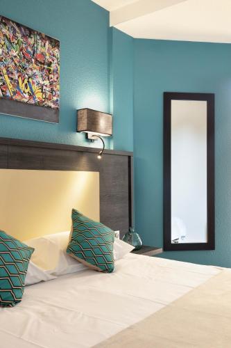 a bedroom with a bed with blue walls and a mirror at Hôtel Le Collier in Antibes