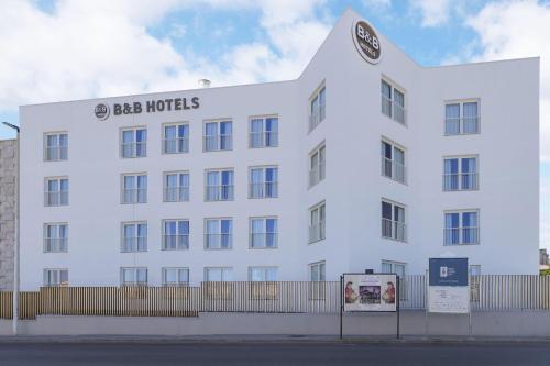 a large white building with a sign on it at B&B HOTEL Sassari in Sassari