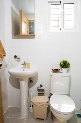 a white bathroom with a toilet and a sink at vacation apartment BANI PERAVIA in Boca Canasta