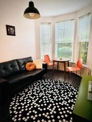 a living room with a black couch and a table at The Duff 1 Bed Flat Walk to Marina Shops and Train in Bangor