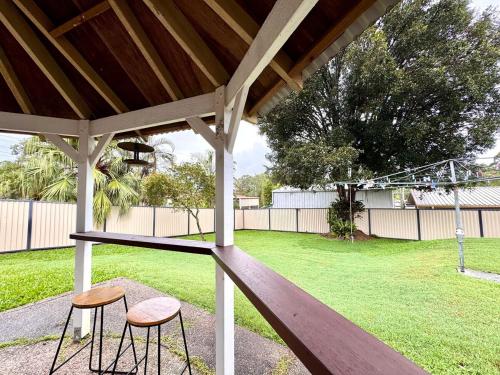 two stools sitting under a gazebo in a yard at Cozy Family Home at Loganholme in Loganholme