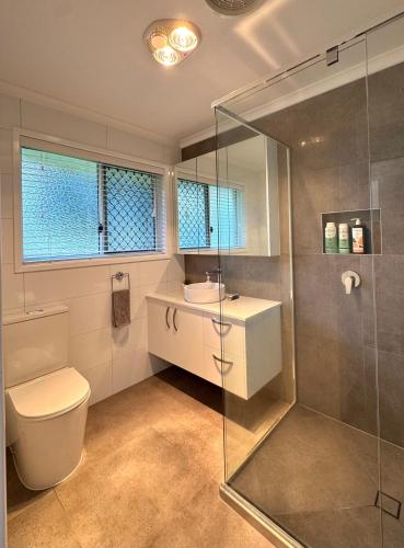 a bathroom with a toilet and a sink and a shower at Cozy Family Home at Loganholme in Loganholme