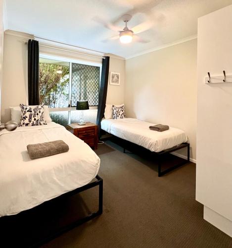 a bedroom with two beds and a window at Cozy Family Home at Loganholme in Loganholme