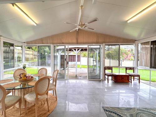 a living room with a ceiling fan and tables and chairs at Cozy Family Home at Loganholme in Loganholme