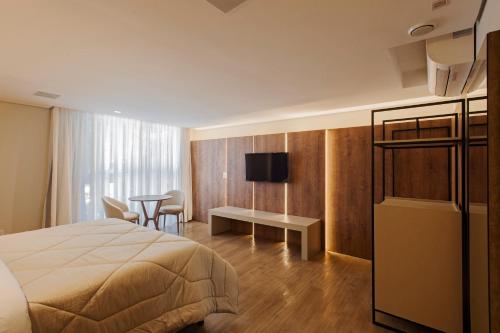 グラマドにあるHarmont Hotelのベッドとテーブルとテレビのある寝室