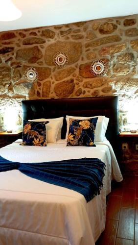 a bedroom with a large bed with a stone wall at Casa do Charco Peneda Gerês in Parada