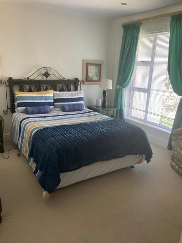 a bedroom with a large bed with blue pillows at Hill Top Guesthouse in Plettenberg Bay