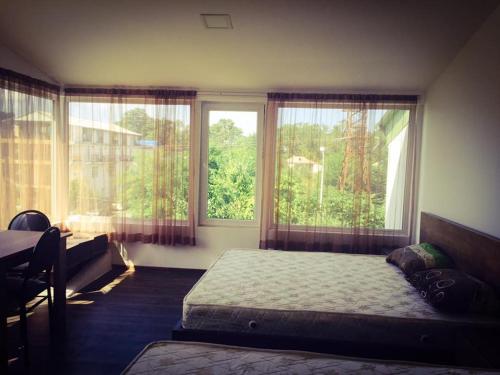 a bedroom with a bed and two large windows at BSG Rustaveli 184 in Kobuleti