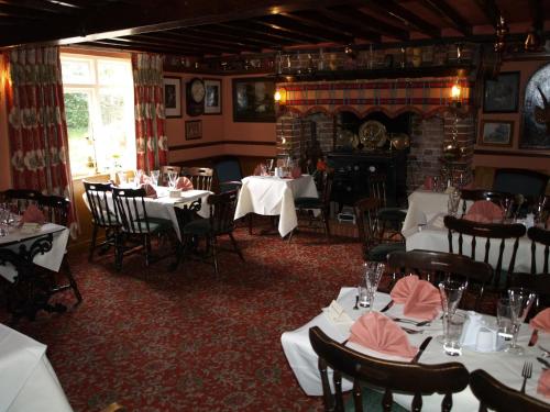 a dining room with tables and chairs and a fireplace at The Olde Windmill Inn in Great Cressingham
