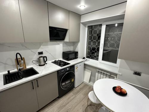a kitchen with white cabinets and a white table at Сатпаева, Телецентр in Taraz