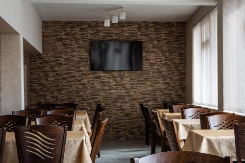 ein Esszimmer mit Tischen und einem TV an einer Backsteinwand in der Unterkunft Dzhorgovata Guesthouse in Govedartsi