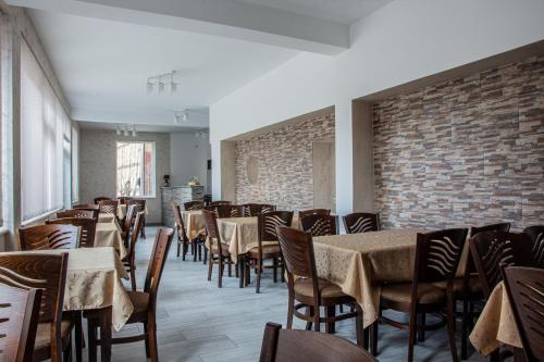 ein Esszimmer mit Tischen und Stühlen und einer Ziegelwand in der Unterkunft Dzhorgovata Guesthouse in Govedartsi
