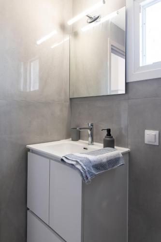a white bathroom with a sink and a mirror at Dore Appartments in Nea Fokea