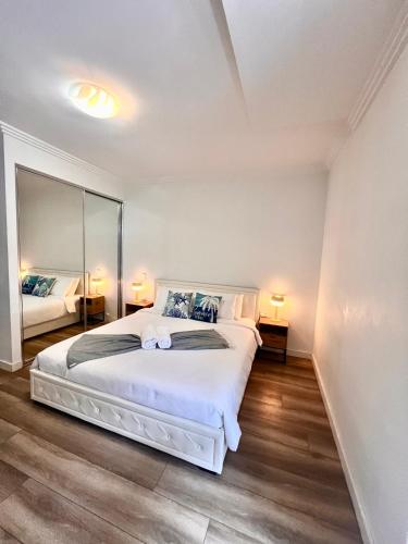 a bedroom with a white bed and a large mirror at Apartment in Turrella in Sydney