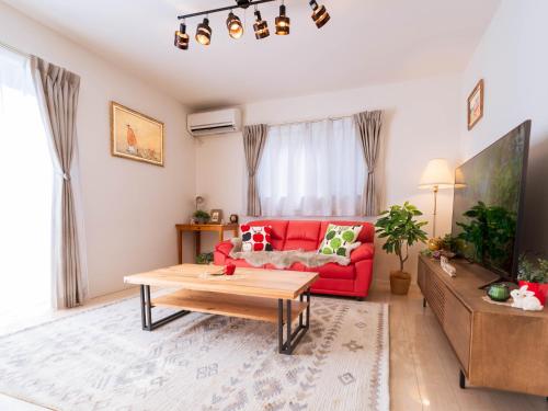 a living room with a red couch and a table at tazuraya-sakuramachi-一棟貸切-無料駐車場 in Takamatsu