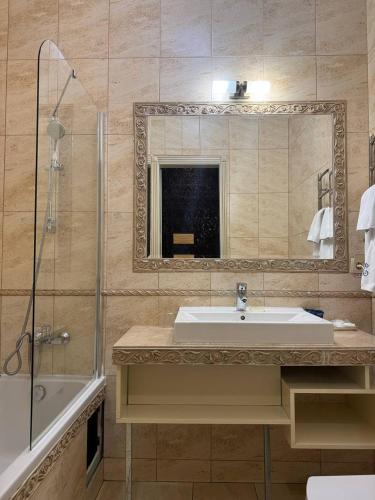 a bathroom with a sink and a shower and a mirror at Metro Hotel Apartments in Odesa