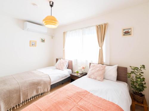 two beds in a room with a window at tazuraya-sakuramachi-一棟貸切-無料駐車場 in Takamatsu