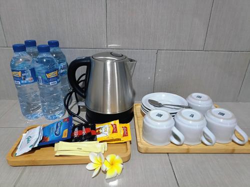 a table with two wooden cutting boards with a coffee pot and water at Rini hotel in Lovina