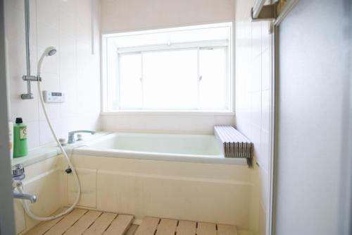 a bathroom with a bath tub and a window at 九十九里シーサイドヴィラ in Tōganemachi