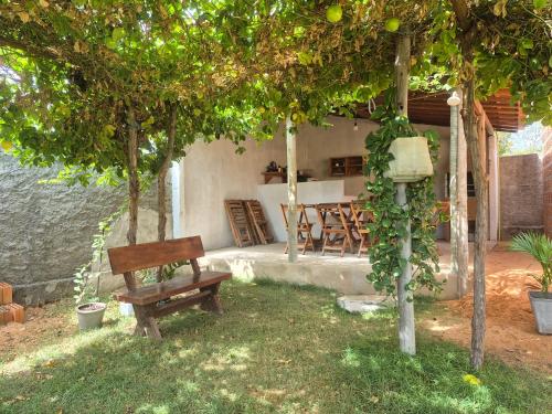 een bank onder een boom in een tuin bij Chalés Brisa do Mar in Amontada