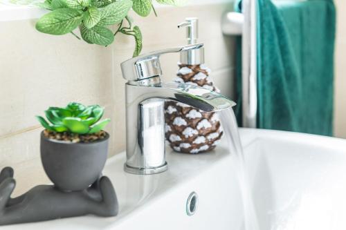 a bathroom sink with a faucet and plants on it at Sleek 2BR city centre Pool table, Parking, Garden, Workspace, weekly sale in Nottingham