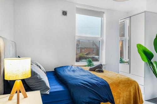 a bedroom with a blue bed and a window at Sleek 2BR city centre Pool table, Parking, Garden, Workspace, weekly sale in Nottingham