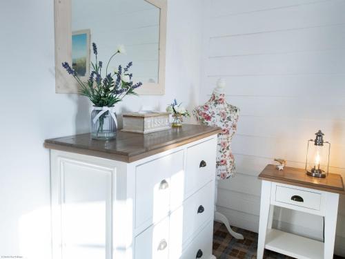 a white cabinet with a vase of flowers on it at Gingerbread Cottage in Filey