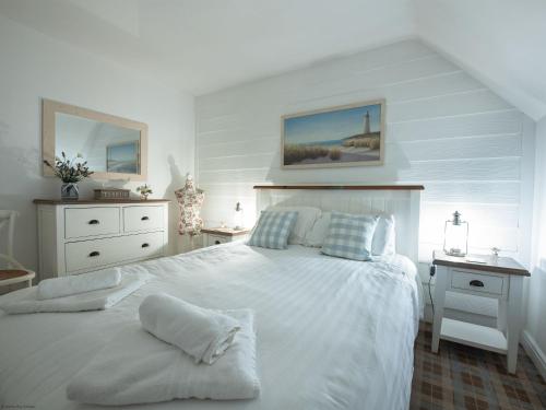 a white bedroom with a large white bed and a desk at Gingerbread Cottage in Filey