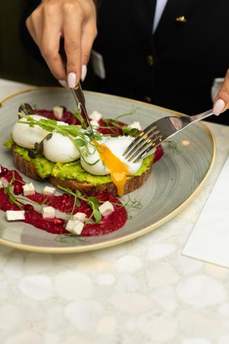 ロンドンにあるザ ライオン ＆ キー ホテルのフォークとナイフでサンドイッチを切る人