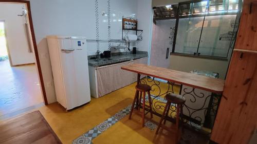 圣安娜杜里亚舒Casa Frida 400m do centro - Serra do Cipo的厨房里有一张桌子和一个冰箱