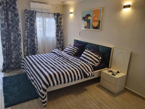 Faso في باماكو: غرفة نوم بها سرير مغطى ببطانية مخططة باللونين الأزرق والأبيض