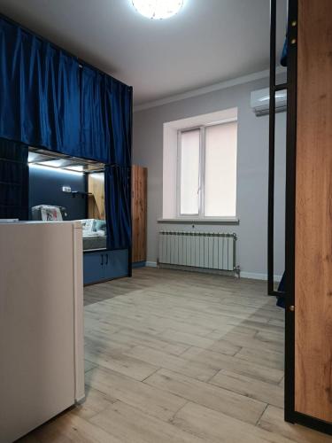 an empty room with a blue curtain and a large window at Kazakhstan-hostel in Astana