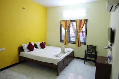 a bedroom with a bed with yellow walls and a tv at Laxmi Palaze in Tallākulam